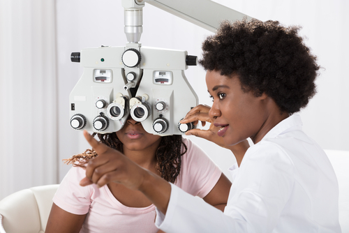 Lady giving girl eye exam. 