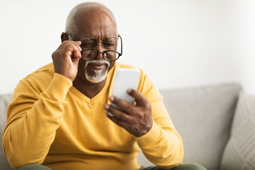 old man struggling to read off of his phone